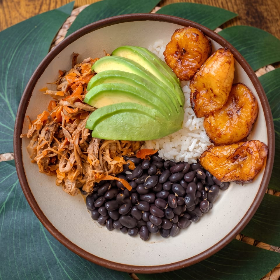 Bowl of white rice, black beans, avocado, shredded vegetables, and grilled orange-glazed protein on tropical leaves.